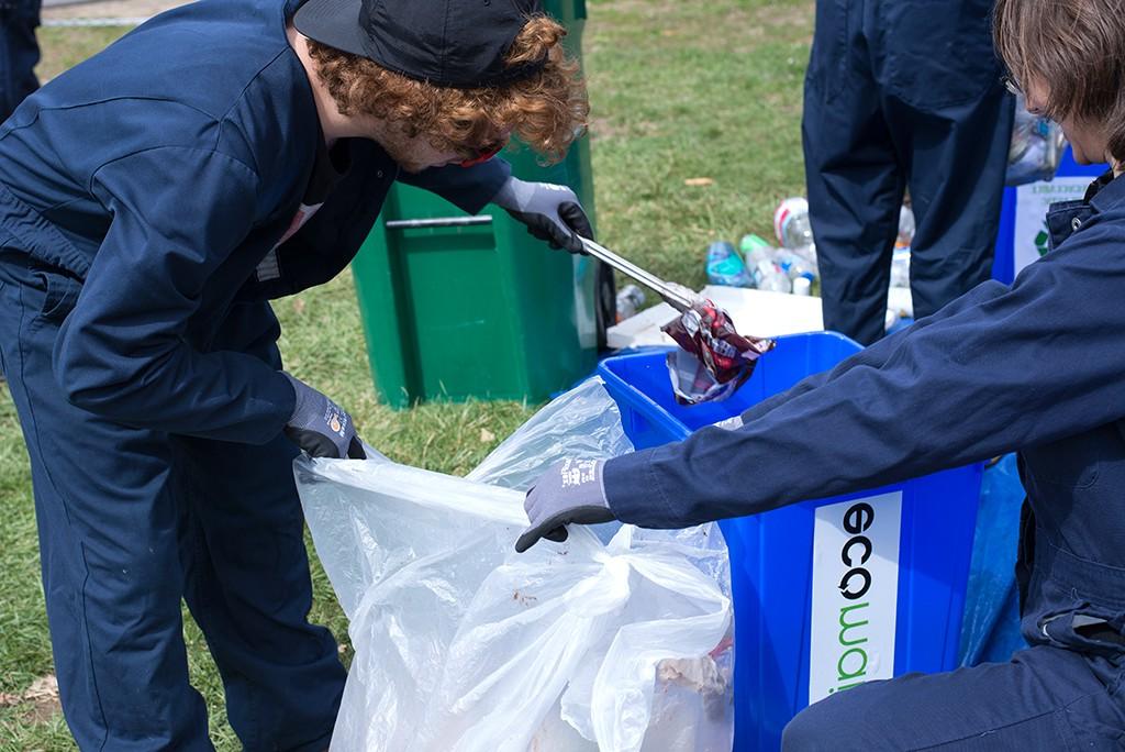 两个学生在一个垃圾袋里寻找可以回收的东西